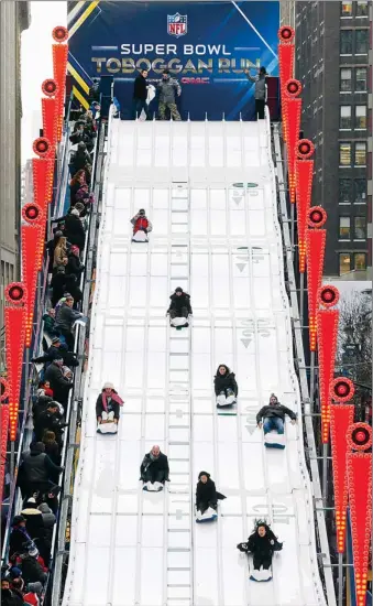  ?? Paul Sancya/Associated Press ?? BLITZ ON BROADWAY
Fans ride the Super Bowl Toboggan Run Friday along Super Bowl Boulevard in New York. The The NFL’s fan experience took over Times Square on a stretch of Broadway that runs from 34th St. to 47th.