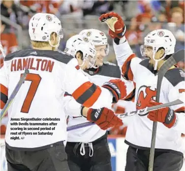  ?? AP ?? Jonas Siegenthal­er celebrates with Devils teammates after scoring in second period of rout of Flyers on Saturday night.