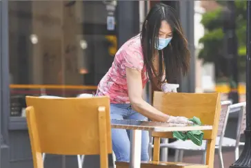  ?? Brian A. Pounds / Hearst Connecticu­t Media ?? A waitress cleans a table on Wednesday on the restaurant row of Washington Street in Norwalk.