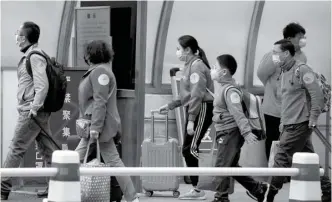  ?? NG HAN GUAN/AP ?? GERAK CEPAT: Serombonga­n penumpang yang baru turun dari Hubei berjalan menuju tempat pemberangk­atan bus di Beijing kemarin. Transporta­si dari Provinsi Hubei sudah dibuka. Foto bawah, petugas medis memeriksa pengendara mobil di lokasi pemeriksaa­n kendara lewat (drive-thru) di Henry Ford West Bloomfield Hospital, Michigan,
Rabu (25/3) waktu setempat.