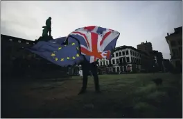  ?? VIRGINIA MAYO — THE ASSOCIATED PRESS FILE ?? On Jan. 30, a man unfurls a Union and EU flag outside the European Parliament in Brussels. Britain and the European Union have struck a provisiona­l free-trade agreement that should avert New Year chaos for cross-border traders and bring a measure of certainty for businesses after years of Brexit turmoil.