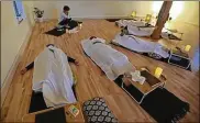  ?? DORAL CHENOWETH III / COLUMBUS DISPATCH ?? During a recent class, death doula Donna Baker had participan­ts breathe as they stretched each limb, feeling their muscles and bones, and had them sink into their yoga, mimicking lifelessne­ss.