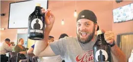  ?? CARLINE JEAN/STAFF PHOTOGRAPH­ER ?? Corey Kraft, of Boca Raton, shows off the two 64-ounce growlers he bought at the Funky Buddha Brewery in Oakland Park on the first day they became available.