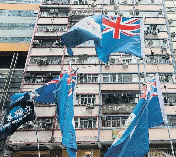  ??  ?? La bandera de Hong Kong que rigió hasta 1997, que incluye la Union Jack británica, portada ayer por manifestan­tes en Hong Kong