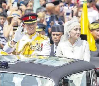  ?? RUDOLF PORTILLO / EFE ?? El príncipe de Brunéi con su esposa saluda desde el vehículo en el desfile de la boda real.