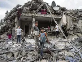  ?? ABDEL KAREEM HANA / ASSOCIATED PRESS ?? Palestinia­ns look at the destructio­n after an Israeli airstrike in Deir al Balah, Gaza Strip, Tuesday.