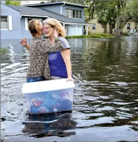  ?? AP/The Florida Times-Union/DEDE SMITH ?? Charlotte Glaze (above photo) gives Donna Lamb a teary hug as she floats out some of her belongings in floodwater from the Ortega River in Jacksonvil­le, Fla., on Monday, after rain from Hurricane Irma flooded the area. (Right photo) A house slides into...