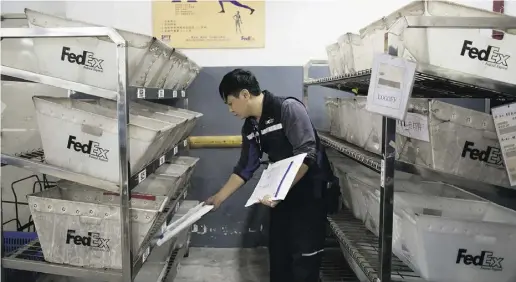  ?? Brent Lewin / Bloo mberg news ?? An employee puts packages into sorting bins at FedEx’s transfer station in Guangzhou, China. Express parcel delivery is booming in China, thanks to a surge in e-commerce.