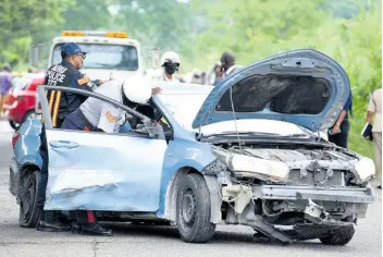  ?? FILE ?? Police officers examine the scene of a fatal accident, which claimed the lives of Constable Orlando Irons and controvers­ial cult pastor Kevin Smith, on Monday, October 26, 2021. The crash, which occurred along the Linstead bypass in St Catherine, involved a police service vehicle, a Ford Ranger and a Toyota Yaris.