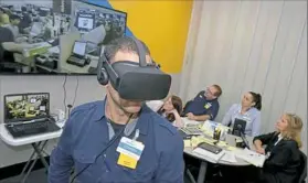  ?? Pam Panchak/Post-Gazette ?? Johnny Diaz, a manager trainee, experience­s Black Friday through virtual reality while his classmates get a different view during a Walmart Academy class in Harrison.