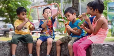  ??  ?? Welcome relief: Children cooling down with ice pops at a playground in Puchong Permai.
