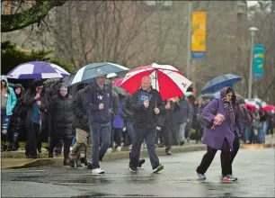  ?? SARAH GORDON THE DAY ?? A tour group hides under umbrellas as they walk through Connecticu­t College’s campus on Monday in New London.