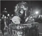  ??  ?? A protester wears a gas mask Sunday outside a Portland police precinct.