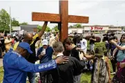  ?? JOSHUA BESSEX / AP ?? A group prays at the site of a memorial for the victims of the supermarke­t shooting outside the Tops Friendly Market that left 10 Black shoppers dead this past May in Buffalo, N.Y.