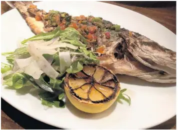  ?? LAUREN DELGADO/ORLANDO SENTINEL PHOTOS ?? Wolfgang Puck Bar &amp; Grill’s whole grilled sea bass is topped with peperonata, a mix of diced olives, onions and peppers.