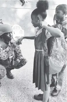  ?? VIA ZOSO FACEBOOK PAGE ?? A member of the zone of special operations joint force interacts with students in Mount Salem, St James, on their first day back to school yesterday.