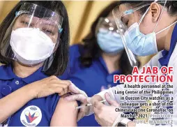  ?? PHOTO BY RUY L. MARTINEZ ?? A JAB OF PROTECTION
A health personnel at the Lung Center of the Philippine­s in Quezon City watches as a colleague gets a shot of the Chinese vaccine CoronaVac on March 1, 2021.