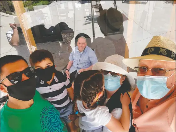  ?? (Courtesy Photo/Dan Sharp) ?? Wake Sharp (center behind plexiglass), 93, visits June 21 with three other generation­s of his family for Father’s Day in Fairfield, Calif. This setup, in which they talk by phone, has enabled the family to visit in person during the coronaviru­s pandemic. Sharp’s son Dan Sharp (right) says, “I don’t know who enjoys it more. My family and I — or dad.” He paused then added, “Probably dad.” Wake Sharp is a World War II veteran who worked for years as a vice president for the Montgomery Ward department store chain.