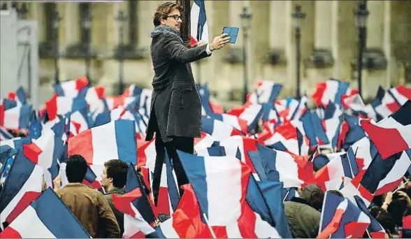  ?? JEFF J MITCHELL / GETTY ?? Un seguidor de Macron fotografía a la multitud congregada el domingo en la explanada del Louvre para celebrar la victoria