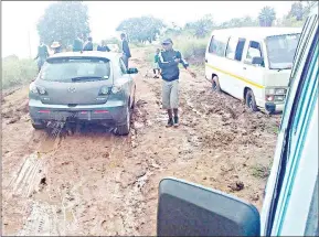  ?? ?? Some of the passengers of kombis pictured on the ground as the public transport vehicles were stuck on the muddy road at Lwandle yesterday morning.