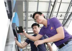  ?? — Reuters ?? An Electrify SG engineer shows how a powerport is installed to record data of photovolta­ic solar panels on a rooftop in Singapore.