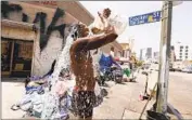  ?? Genaro Molina Los Angeles Times ?? A RESIDENT of skid row washes himself with water from a hydrant during a heat wave in 2021.