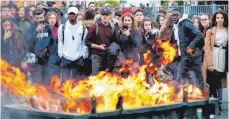  ?? FOTO: DPA ?? Schüler stehen hinter einer brennenden Mülltonne: Seit Wochen demonstrie­ren die Gelbwesten gewaltsam gegen Steuererhö­hungen.
