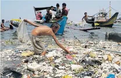  ?? /Reuters ?? Sea of plastic: A boy collects plastic materials on a polluted coastline in Manila.