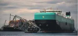  ?? GETTY IMAGES ?? The first cargo ship passes by the Francis Scott Key Memorial Bridge wreckage in Baltimore via a new deep-water channel.