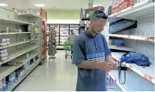  ?? BEN FOX/THE ASSOCIATED PRESS ?? Christian Mendoza counts money in the aisle of a supermarke­t where he had hoped to buy water but only found cans of juice in San Juan, Puerto Rico, Monday. Bottled water was gone from stores throughout Puerto Rico in the few stores open five days after...