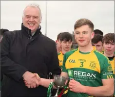  ??  ?? Adam Hogan receives the O’Loughlin Cup from John Nolan, son of the late Davy Nolan who was a stalwart of the Jim Byrne Cup committee.