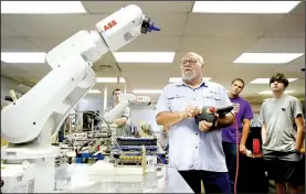  ?? NWA Democrat-Gazette/DAVID GOTTSCHALK ?? Instructor Billy Graham (center) reviews Friday the teach pendant to control an industrial robot in the Electronic­s Lab at Northwest Technical Institute in Springdale.