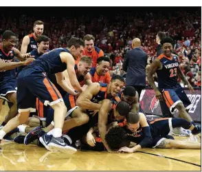  ?? AP/TIMOTHY D. EASLEY ?? Teammates pile onto Virginia guard De’Andre Hunter following his winning three-pointer at the buzzer as the Cavaliers defeated Louisville 67-66 on Thursday in Louisville, Ky.