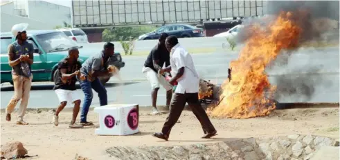  ?? Photo: NAN ?? Sympathize­rs help a dispatch rider to put out fire from his motorcycle at Nnamdi Azikiwe Ring Road, by Julius Berger junction in Abuja yesterday