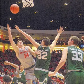  ?? GREG SORBER/JOURNAL ?? New Mexico’s Dane Kuiper (14) shoots while being guarded by Colorado State’s Nico Cavacho (32) as CSU’s Braden Koelliker (33) watches.