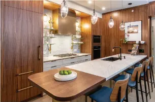  ?? MITCHELL HUBBLE PHOTOS SUTTON GROUP REALTY ?? The long kitchen island features a four-seat breakfast bar with a marble-and-walnut counter, a custom ceramic-tile backsplash with built-in brass and glass shelves and built-in appliances.