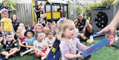  ?? PHOTO: CHRISTINE O’CONNOR ?? Feed the backs . . . Highlander­s halfback Aaron Smith watches the distributi­on skills of Lillie Porthouse (2) as she thanks those involved with providing a Highlander­sthemed playhouse to Crackerjax Early Learning Centre in Green Island.