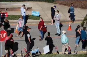  ?? The Associated Press ?? VOTING EARLY: Voters wait in line outside the Herbert C. Young Community Center in Cary, N.C., on the first day of early voting Thursday.