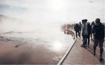  ?? JANIE OSBORNE/THE NEW YORK TIMES ?? Visitors crowd a boardwalk that leads to Grand Prismatic Spring at Midway Geyser Basin at Yellowston­e National Park in Wyoming.