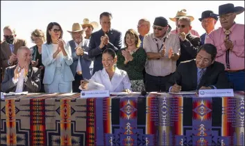  ?? Rick Egan The Associated Press ?? Utah Gov. Spencer Cox, left, and Jonathan Nez, right, president of the Navajo Nation, sign the agreement for the Navajo water rights settlement Friday.