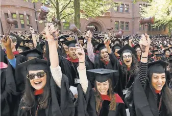  ?? 2014 PHOTO BY STEVEN SENNE, AP ?? Graduates from the Harvard Law School wave gavels and cheer during commenceme­nt ceremonies, in Cambridge, Mass.