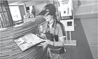  ?? JOE RAEDLE, GETTY IMAGES ?? McDonald’s crew member Crystalle Martin carries an order to a customer’s table in Miami. The company’s new self-ordering kiosks are having a positive effect on sales.