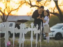  ?? JAY JANNER/AUSTIN AMERICAN-STATESMAN VIA AP ?? Meredith Cooper of San Antonio, Texas, and her 8-year-old daughter, Heather, visit a memorial Monday near First Baptist Church in Sutherland Springs, Texas. The gunman of a deadly shooting at the church had a history of domestic violence, authoritie­s...