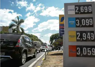  ?? Pedro Ladeira/Folhapress ?? Fila de veículos em posto que ainda não havia reajustado os combustíve­is em Brasília