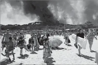  ?? CLAUDE PARIS/AP PHOTO ?? Sunbathers are evacuated from the beach in Le Lavandou, French Riviera, Wednesday as plumes of smoke rise in the air from burning wildfires. French authoritie­s ordered the evacuation of up to 12,000 people around a picturesqu­e hilltop town in the...