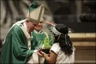  ?? ALESSANDRA TARANTINO-THE ASSOCIATED PRESS ?? An Amazon indigenous girl gives Pope Francis a plant during the offertory of a Mass for the closing of Amazon synod in St. Peter’s Basilica at the Vatican, Sunday.