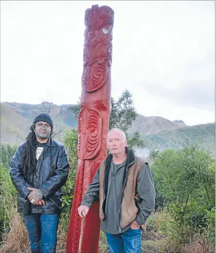  ??  ?? Carver Dane Kingi, left, and Friends of Mawai Hakona Stream leader Bart Hogan by the first of two pou blessed and unveiled at the site. Kingi said the rahui post features a kaitiaka figure at the top, representi­ng a guardian, and a pito (umbilical...