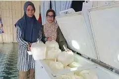  ?? ?? SITI Shafikah (kiri) bersama kakaknya, Siti Norhayati menunjukka­n debu ubi kayu yang dihasilkan.