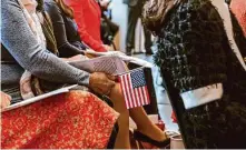  ?? ?? A participan­t holds an American stick flag during the ceremony, at which women from 17 countries became citizens.