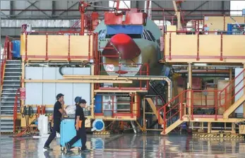  ?? EPA ?? Workers walk next to the fuselage section of a plane at the Airbus A320 family final assembly line in Tianjin.